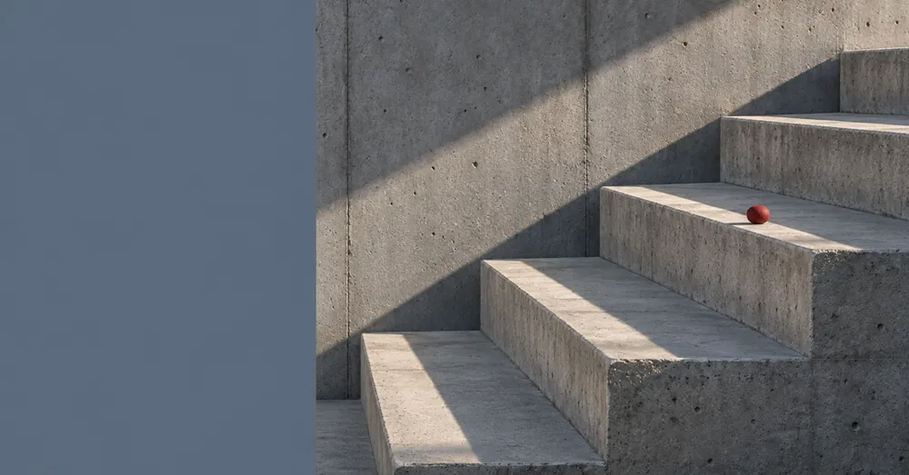 Escada de concreto com degraus largos e um pequeno detalhe vermelho apoiado em um deles.